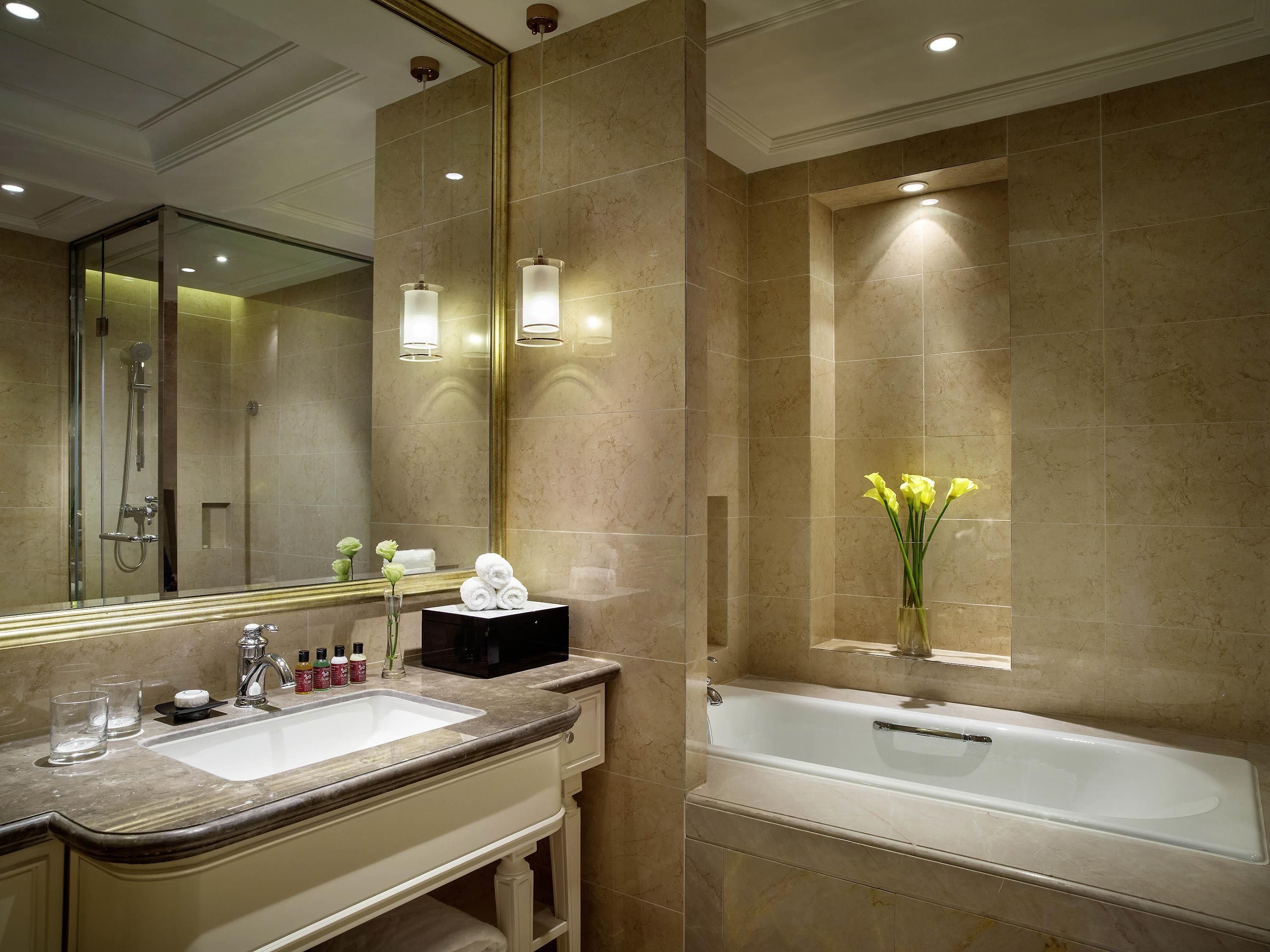 Un baño moderno con lavamanos doble, un espejo grande, una bañera y un florero con flores.