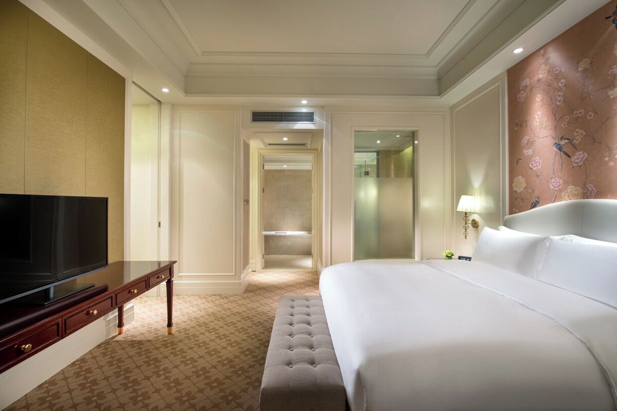 Una habitación de hotel con una cama grande, un televisor de pantalla plana, un escritorio y un vestidor.