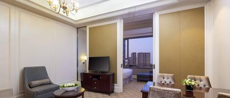 Una camera d'albergo con televisione, angolo salotto e vista sugli edifici.