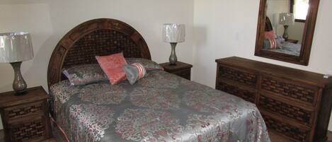 A bedroom with a bed, two nightstands, a dresser, and a mirror.