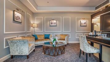 A hotel room with a sofa set, a coffee table, and a dining area.
