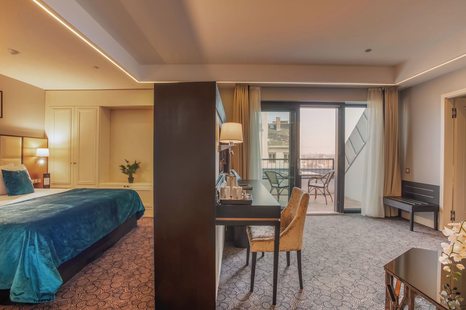Une chambre d’hôtel comprenant un lit, un bureau, une chaise, une table et un balcon avec des chaises.