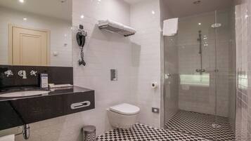 A modern bathroom with a black and white checkered floor, a glass-enclosed shower, and a black countertop with a sink and mirror.