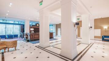 A hotel lobby with a reception desk, seating area, and a large column structure.