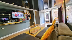 A modern living room with a sofa, a coffee table, and a TV displaying a cycling event. - Letstay Hotel - Adult Only +12 (Antalya)