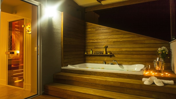 A wooden staircase leading to a spa area with a large bathtub, a small shelf with toiletries, and a door leading to another room. - Letstay Hotel - Adult Only +12 (Antalya)