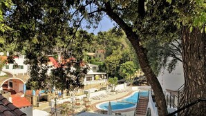 A pool area with lounge chairs, a small pool, and a staircase leading up to a building with a red roof. - Alta Galdana (Ciutadella de Menorca)
