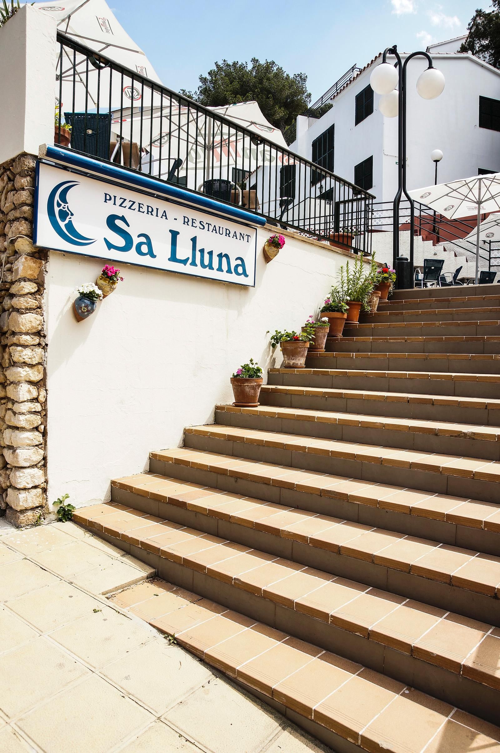 Una escalera conduce a un edificio con un letrero que dice 'Pizzeria - Restaurant Sa Luna'.