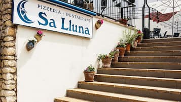 Una escalera conduce a un edificio con un letrero que dice 'Pizzeria - Restaurant Sa Luna'.