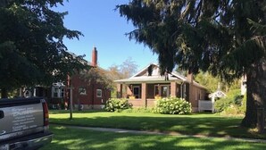 Una casa residencial con un césped cuidado, una chimenea de ladrillo y un porche pequeño.
