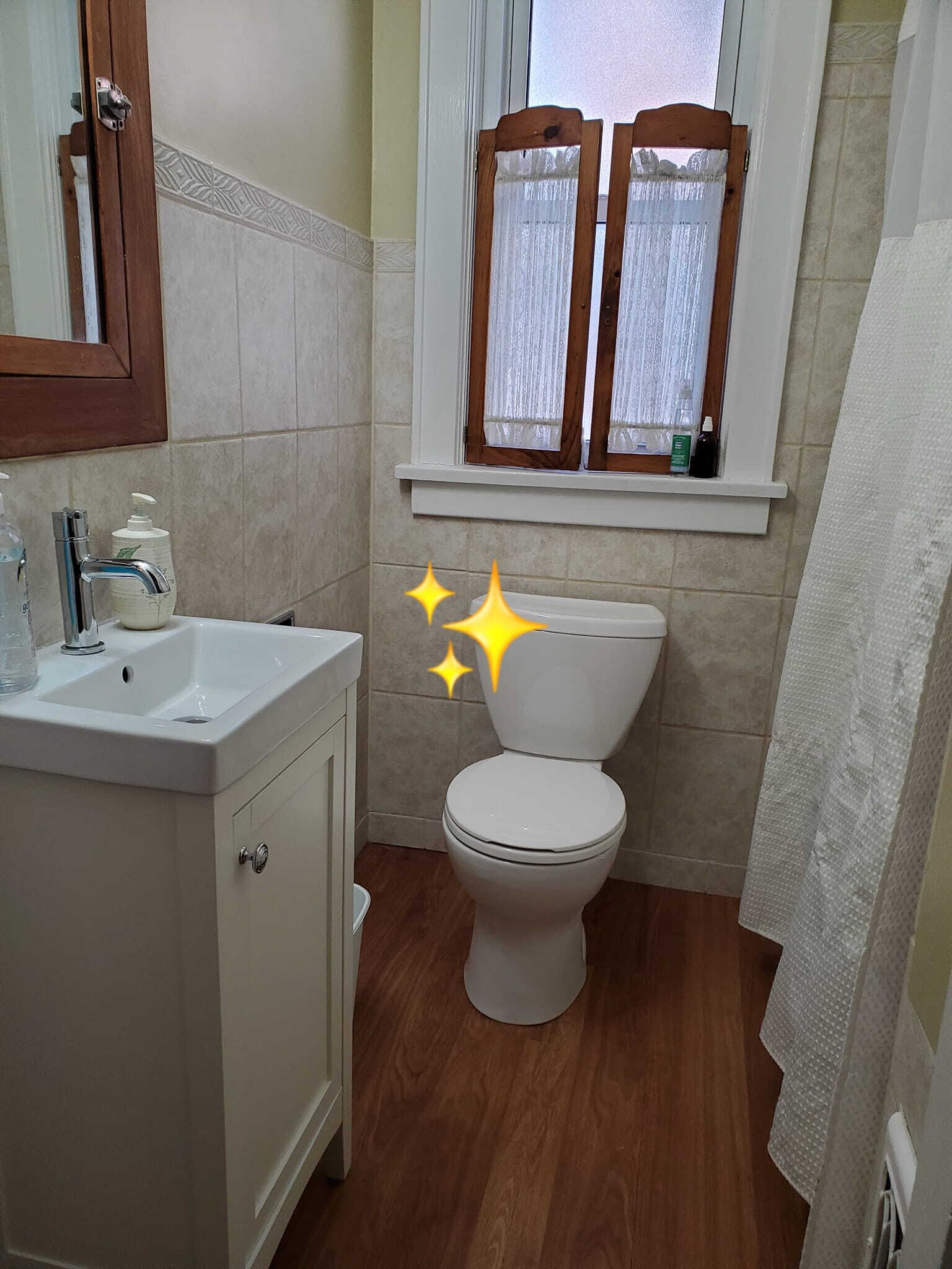 A bathroom with a white sink, a toilet, and a window with wooden shutters.