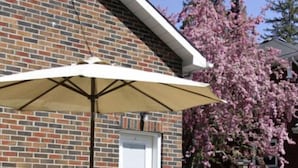 Un patio con mesa y sillas, una parrilla y un árbol en flor.