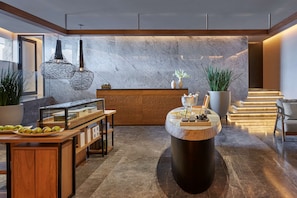 Welcome to our hotel lobby, featuring a reception desk, a central table with potted plants, and a cozy seating area.