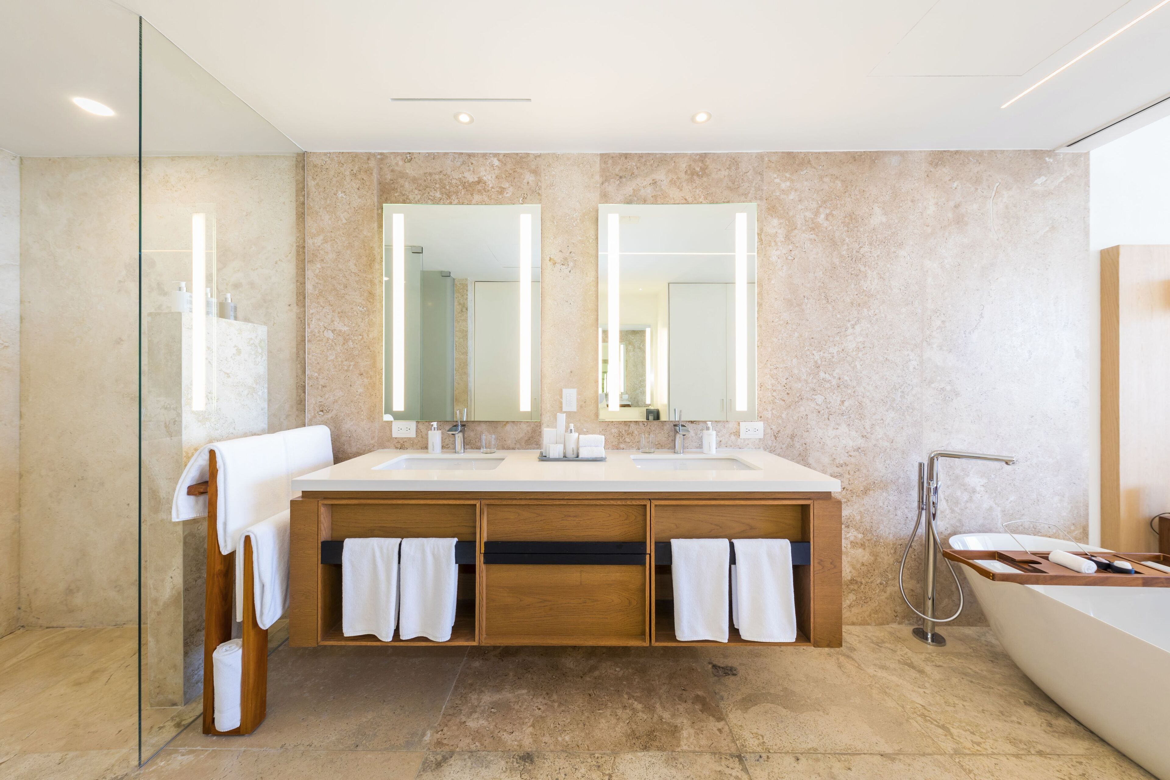 Ein modernes Badezimmer mit einem großen Waschtisch, zwei Waschbecken, einer Badewanne und einer Duschkabine aus Glas.