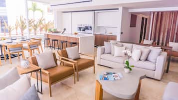 A modern living room with a sofa, chairs, a coffee table, and a kitchen area in the background.
