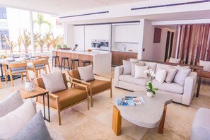 A modern living room with a sofa, chairs, a coffee table, and a kitchen area in the background.