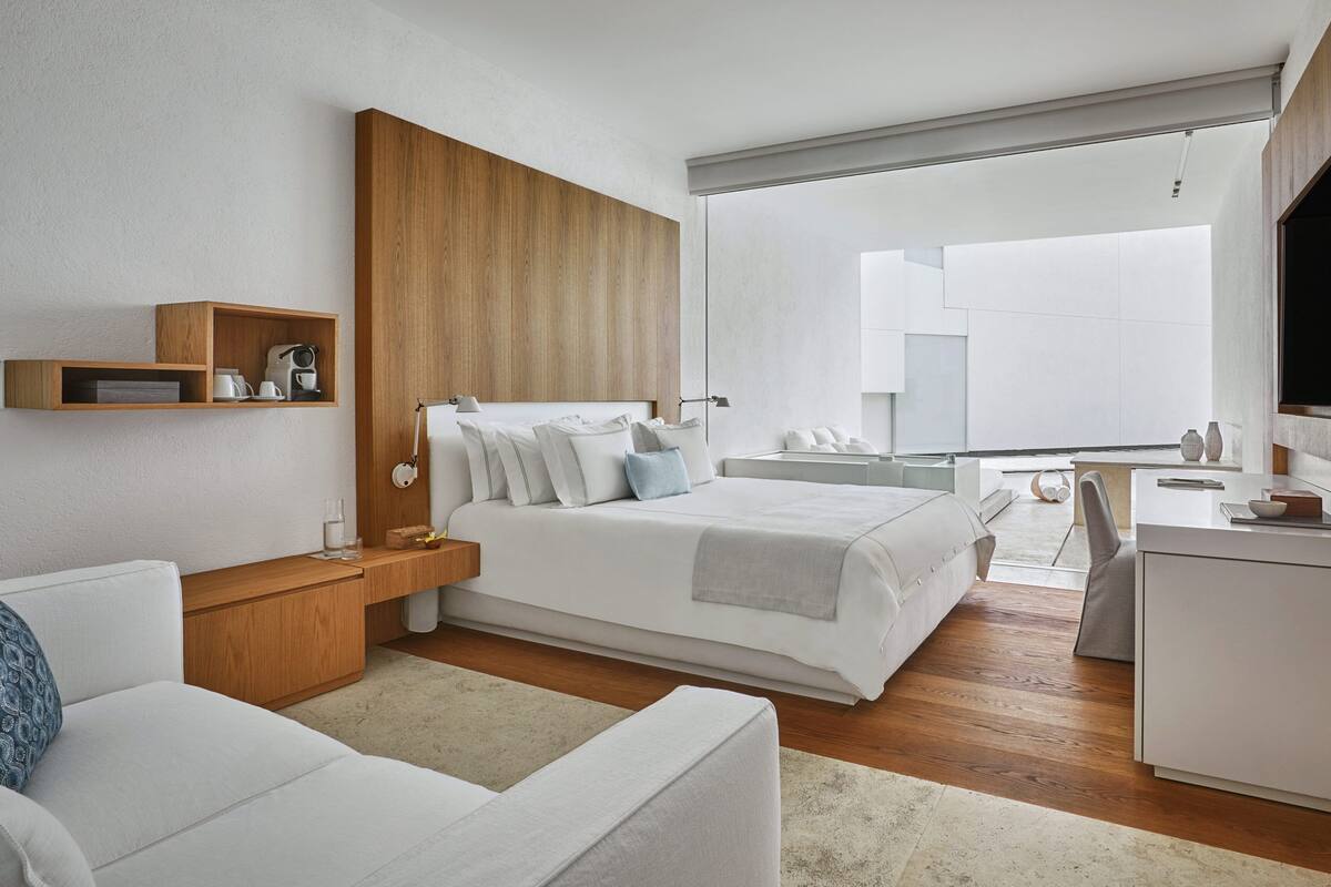 Una habitación de hotel moderna con una cama grande, un escritorio, una silla y un televisor.