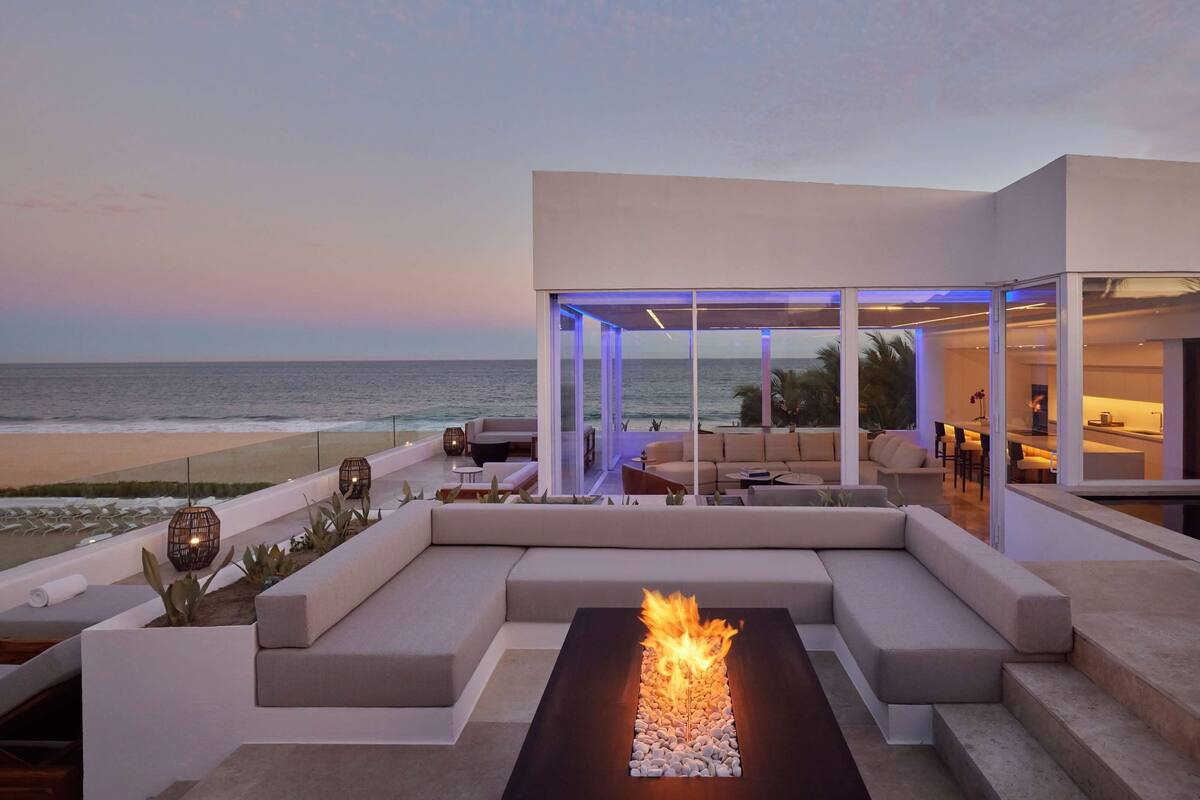 Un espacio exterior moderno para disfrutar al aire libre, con una chimenea, asientos y vistas al océano.