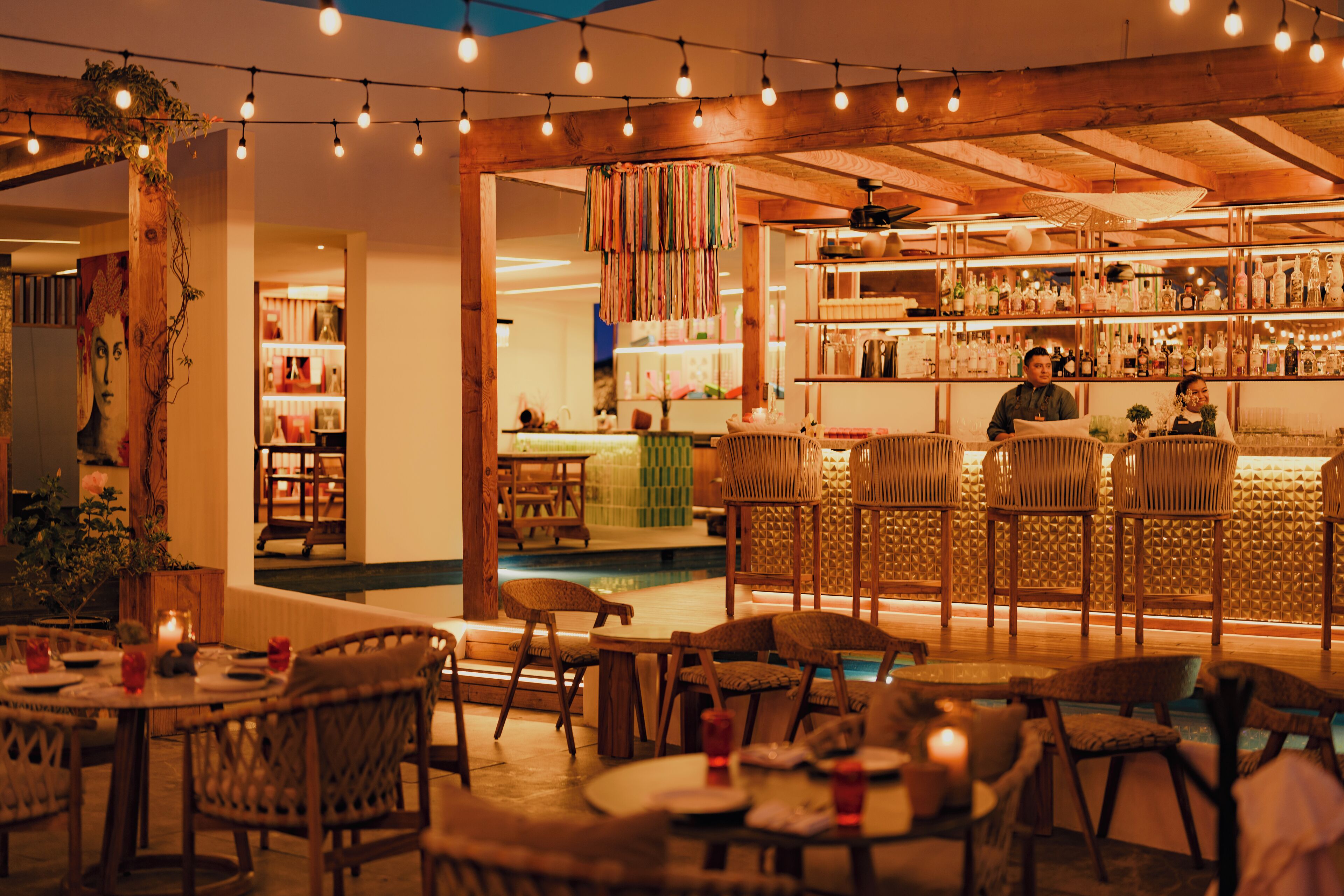 A cozy restaurant with wicker furniture, a bar area, and a pool.