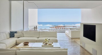 A modern living room with a large window overlooking a beach.
