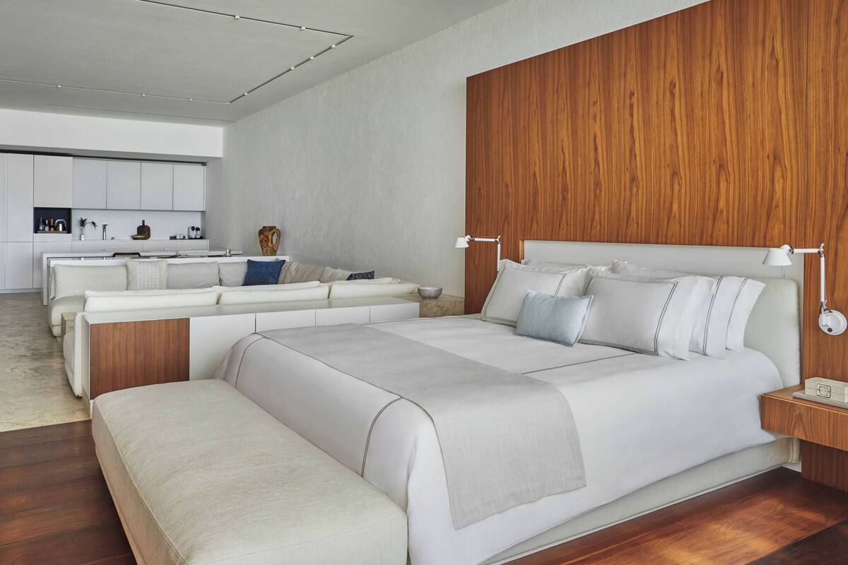 Un dormitorio moderno con una cama grande, mesitas de noche y un panel de pared de madera integrado.