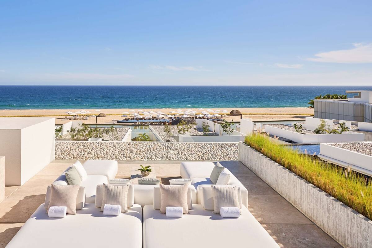 Terraza en la azotea con sillones blancos y vistas a la playa y al océano.