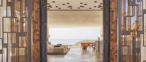 An open doorway leading to a beach view with a seating area and a dining table.