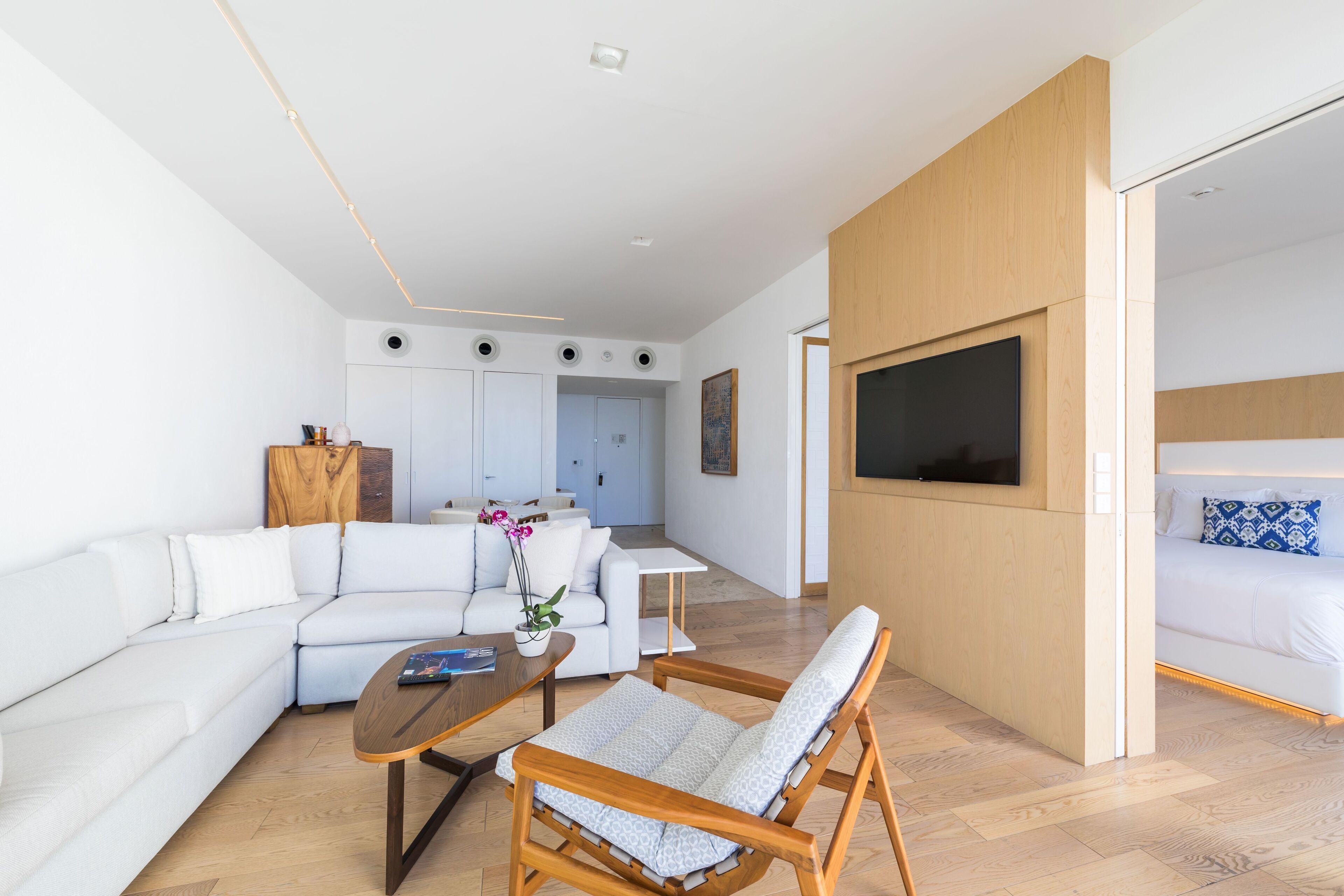 Una sala de estar moderna con sofá, mesa de centro y televisor instalado en la pared.