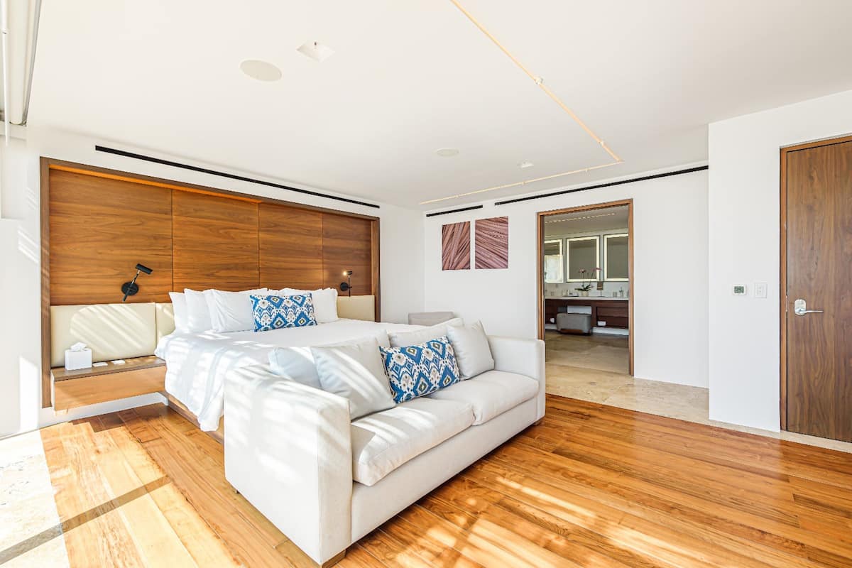 Un dormitorio moderno con una cama grande, cabecera de madera y piso de madera.