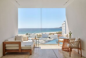 Una habitación moderna con un amplio ventanal que da a una playa y una piscina.