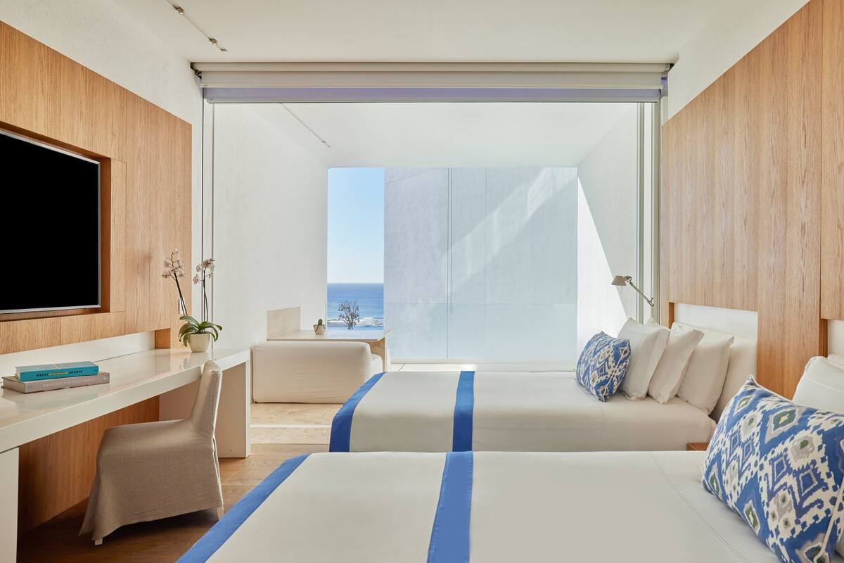Habitación de hotel moderna con una cama grande, un escritorio y vista al océano.