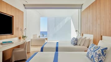 Quarto de hotel moderno com uma cama grande, uma escrivaninha e vista para o oceano.