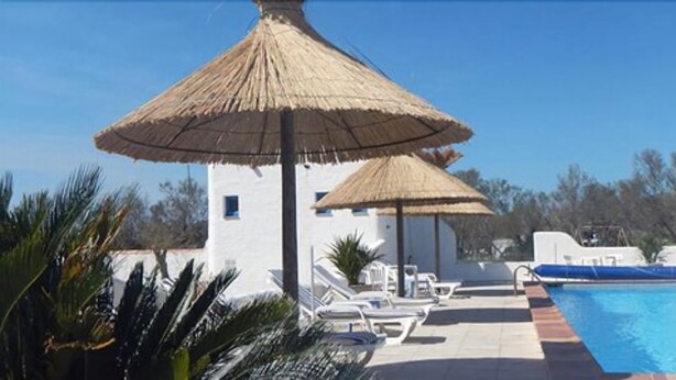 A pool area with lounge chairs and thatched umbrellas. - Hôtel Clamador (Saintes-Maries-de-la-Mer)