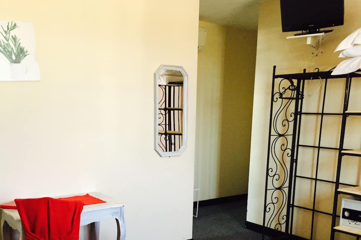 Hotelkamer met een bed, bureau, stoel, televisie en een raam met tralies.