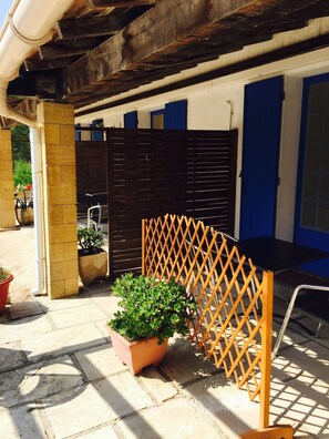 A patio area with a wooden lattice fence, a potted plant, and a black table.