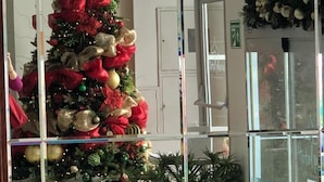 Un árbol de Navidad con adornos rojos y dorados, una araña y vistas del vestíbulo del hotel.