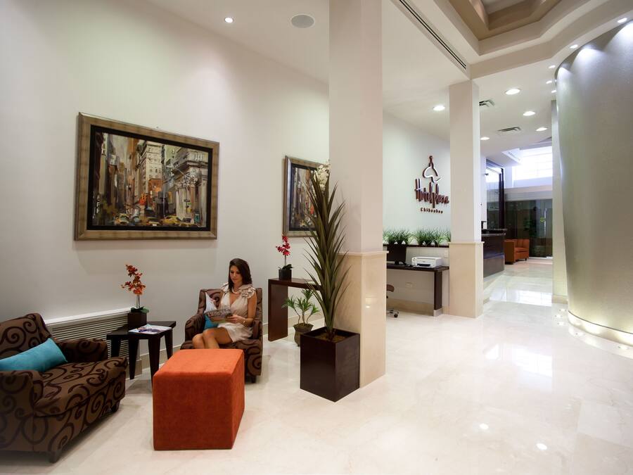 A modern lobby with a large painting, a reception desk, and a seating area with a sofa and ottoman.