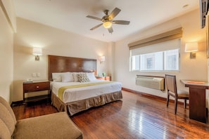 A hotel room with a bed, bedside table, lamp, desk, chair, and a ceiling fan. - Hotel Plaza Chihuahua (Chihuahua)