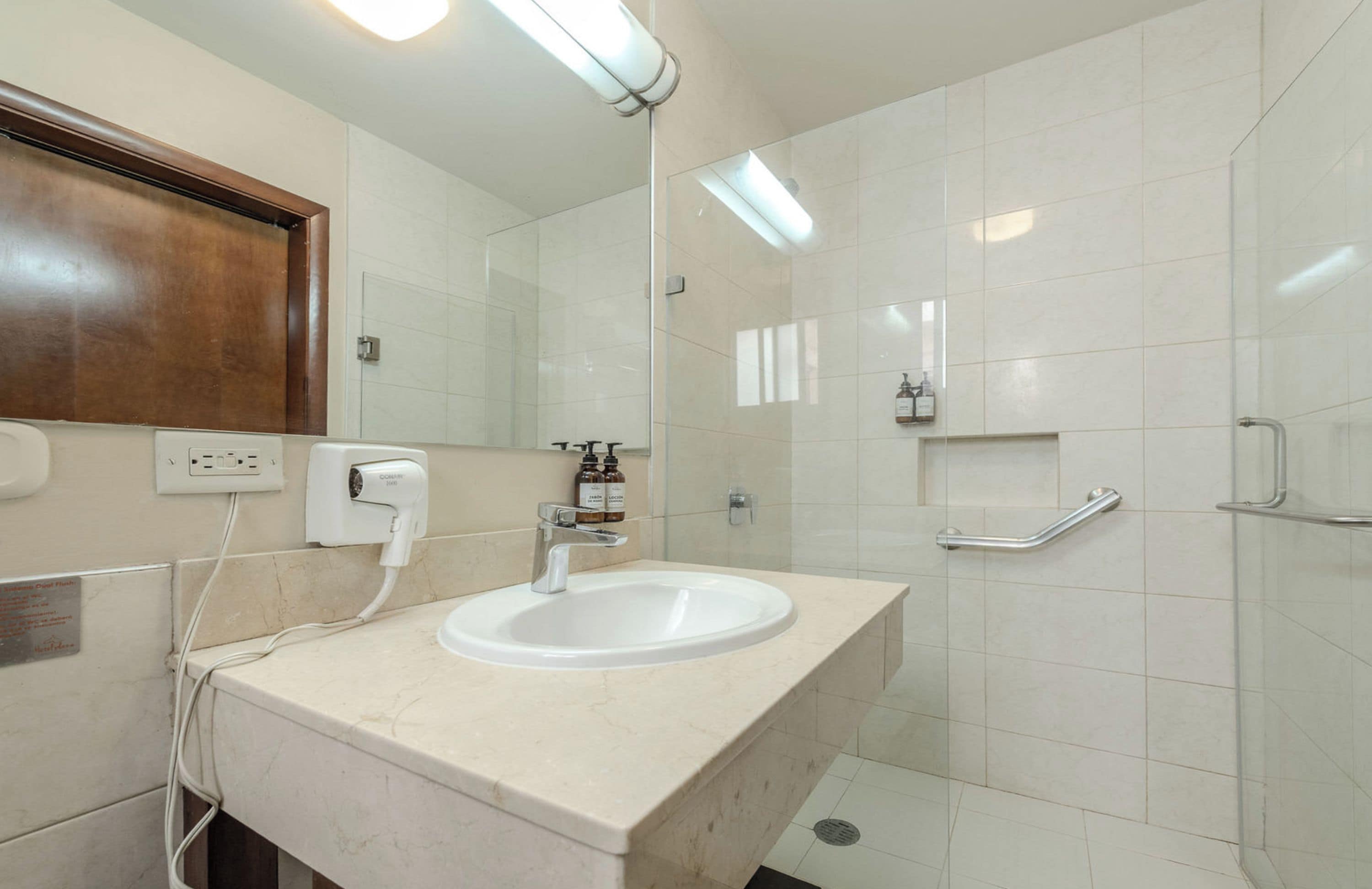 A bathroom with a white sink, mirror, and tiled walls.