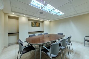 A conference room with a round table, six chairs, recessed ceiling lighting, and a wall-mounted painting. - Hotel Plaza Chihuahua (Chihuahua)