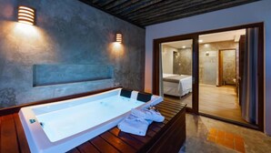 Un baño moderno con una bañera grande, un banco de madera y dos luces fijadas a la pared.