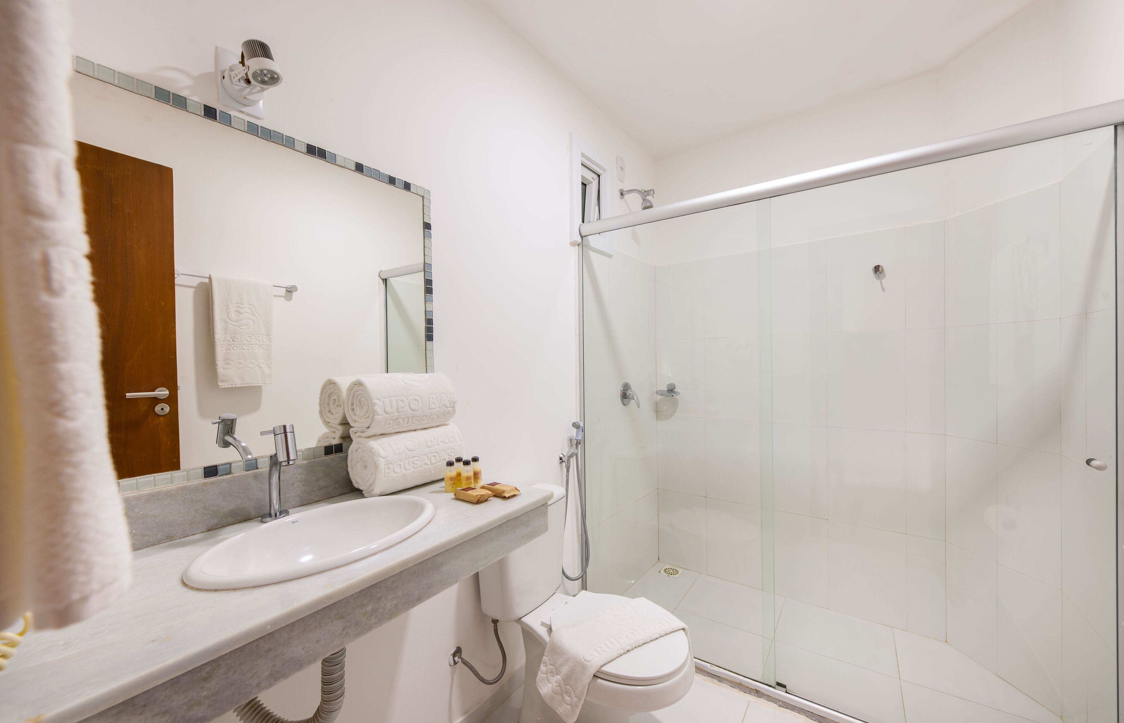 Une salle de bain moderne avec une douche à parois de verre, un lavabo blanc et un miroir au-dessus.