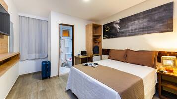 A hotel room with a bed, bedside table, lamp, and a large painting on the wall.