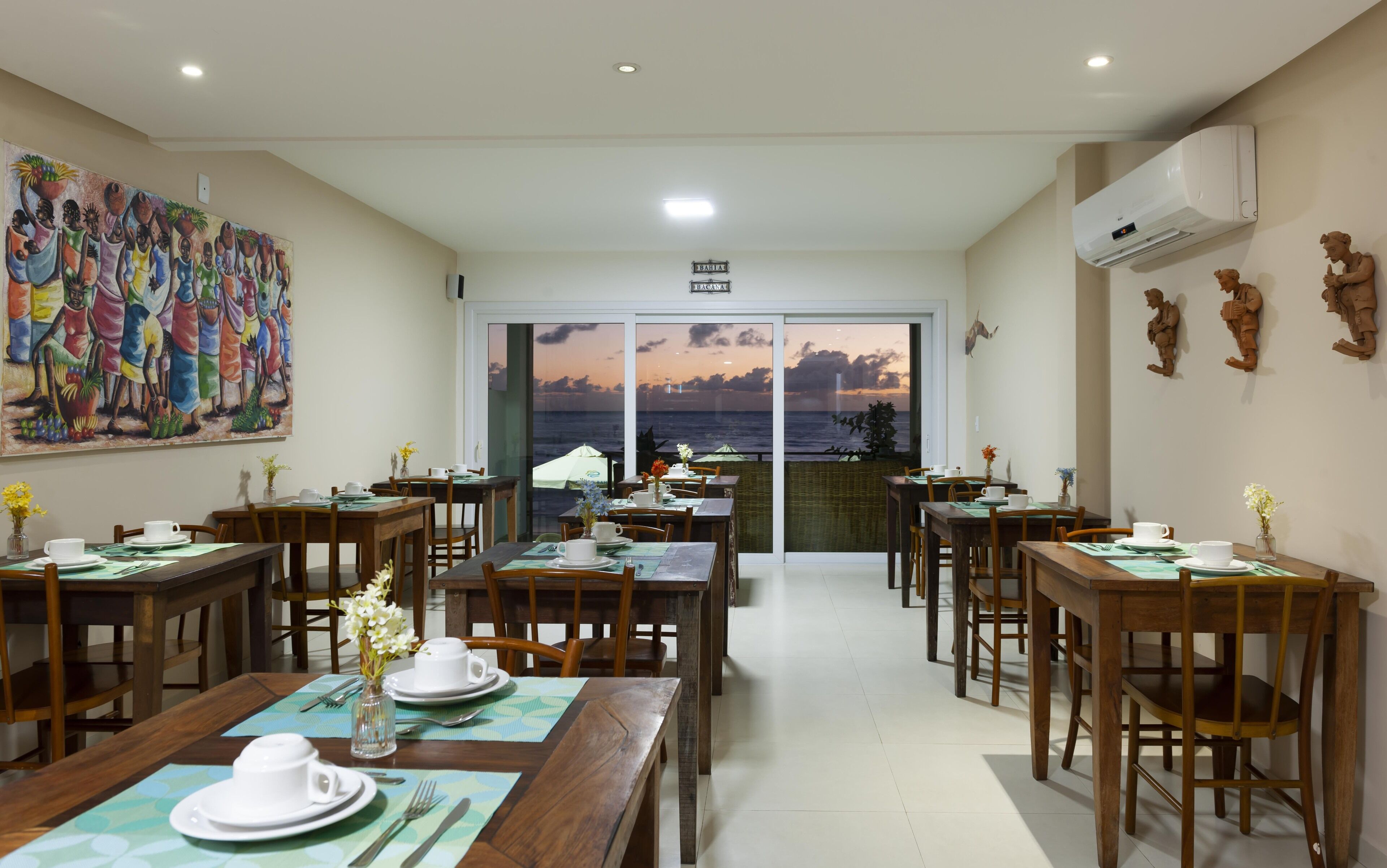 A dining area with multiple tables, chairs, and a large painting on the wall.