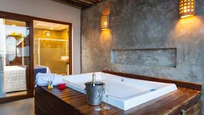 Un baño moderno con una bañera grande, un tocador de madera y una cabina de ducha de vidrio.