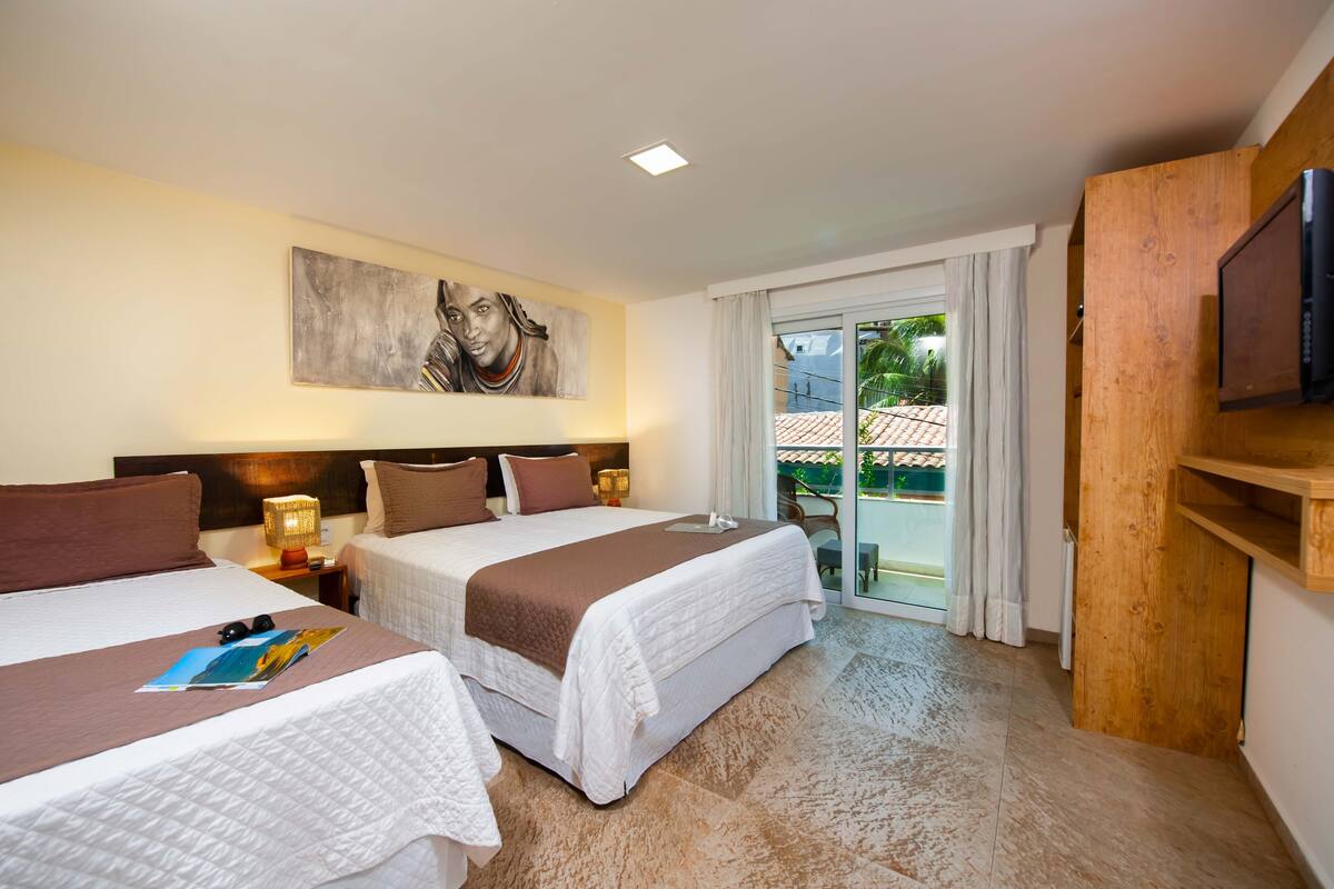 Habitación de hotel con dos camas, un cuadro en la pared, televisión y balcón con vistas.