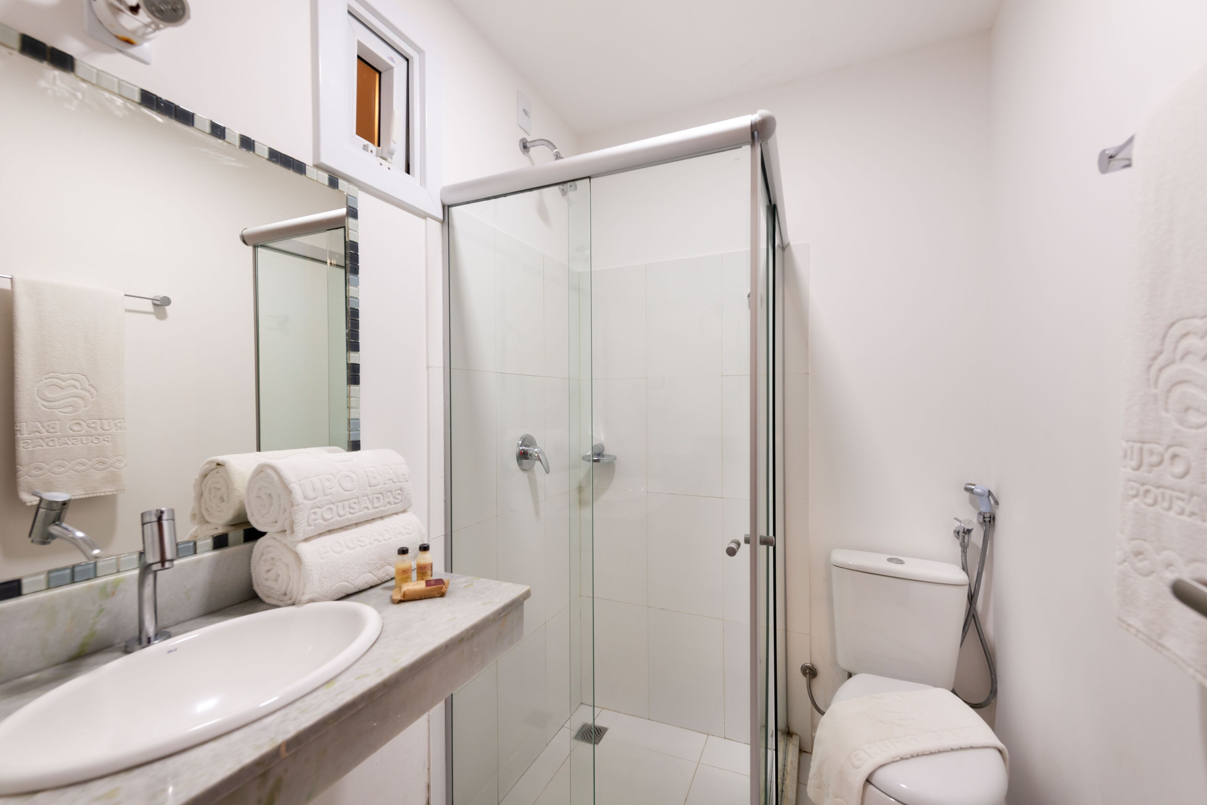 A modern bathroom with a glass-enclosed shower, a white sink, and a toilet.