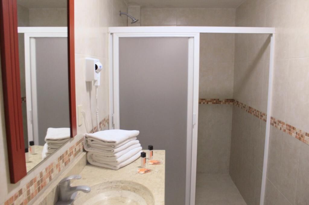 Un baño con lavamanos, espejo, toallero y cabina de ducha.
