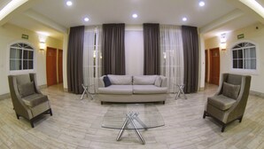 A spacious living area with a large sofa, two armchairs, and a glass coffee table. - Hotel River Poliforum (León)