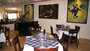 Un restaurant où les tables sont dressées pour le service, et où les murs sont ornés d’œuvres d’art.